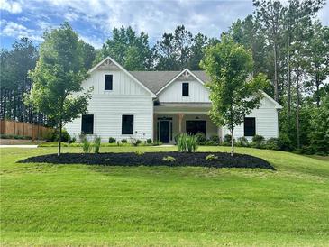 Charming, new construction, two-story home with a white exterior, dark windows and a well-manicured lawn at 3445 Henderson Dr, Cumming, GA 30041