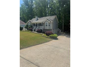 Charming two-story home with gray siding, landscaped yard, and inviting front porch and a view of the driveway at 72 Victorian Cir, Dallas, GA 30157