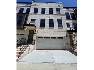 Modern townhome featuring a two-car garage, neutral brick facade, and elegant black window trim at 1107 Rivard Nw Cir, Atlanta, GA 30318