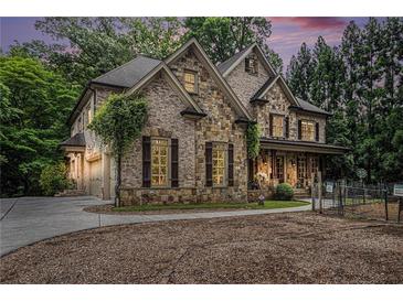 Stunning stone and brick home with a well-manicured lawn and a circular driveway at 3809 Wieuca Ne Rd, Atlanta, GA 30342