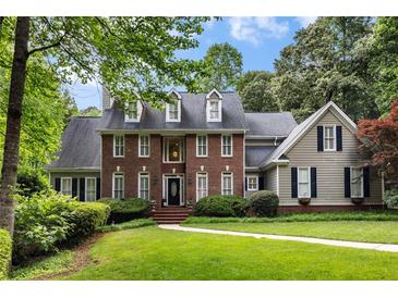 Beautiful two story brick home with dormer windows and lush green landscaping at 530 Twinflower Ct, Roswell, GA 30075