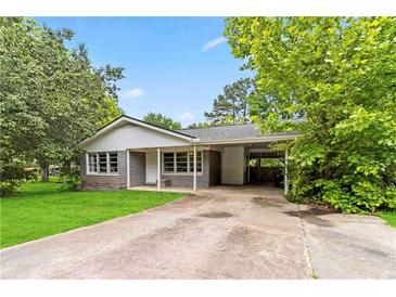 Charming single-story home with a gray brick facade, mature trees and a carport at 1176 Cardinal Ne Rd, Conyers, GA 30012