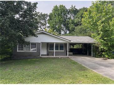 Charming single-story home with a covered parking area and a well-maintained front yard surrounded by mature trees at 1176 Cardinal Ne Rd, Conyers, GA 30012