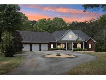 Beautiful brick home featuring a circular driveway, three-car garage, and manicured landscaping under a colorful sunset at 270 Morrow Rd, Newborn, GA 30056