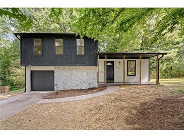 Charming split-level home featuring stone accents, a covered porch, and an attached garage at 5401 Martins Crossing Rd, Stone Mountain, GA 30088