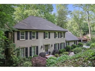 Charming brick home featuring mature landscaping, black shutters and a welcoming front entrance at 960 Lost Forest Dr, Sandy Springs, GA 30328