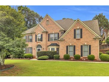 Stately brick home boasts manicured lawn, mature trees, and classic architectural details at 947 Summer Forest Drive, Suwanee, GA 30024