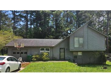 Charming two-story home with a basketball hoop on the garage, neutral siding, and mature trees at 4287 Ridgetop Trl, Ellenwood, GA 30294
