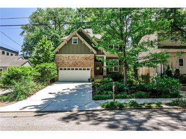 Charming home with a stone and siding exterior, lush landscaping, and a driveway leading to an attached garage at 1249 Francis Nw St, Atlanta, GA 30318
