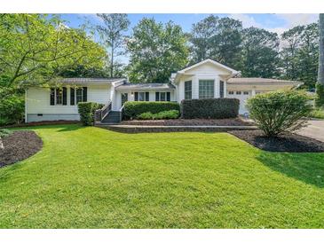 Charming home featuring a lush green lawn, mature landscaping, and a welcoming facade at 4458 Trickum Ne Rd, Marietta, GA 30066