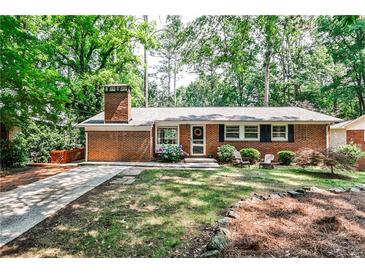 Charming brick home with a well-manicured lawn, mature trees, and cozy front porch with seating at 1082 Greenbriar Cir, Decatur, GA 30033