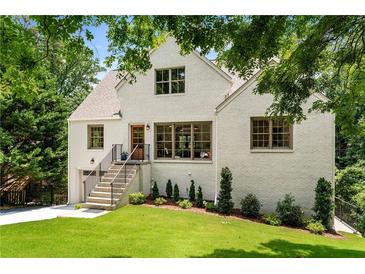 Beautifully landscaped two-story home with white painted brick, inviting front porch, and lush greenery at 1327 Harvard Ne Rd, Atlanta, GA 30306