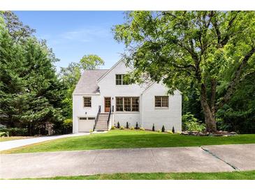 Charming white brick home featuring a landscaped yard, inviting entryway, and attached garage at 1327 Harvard Ne Rd, Atlanta, GA 30306