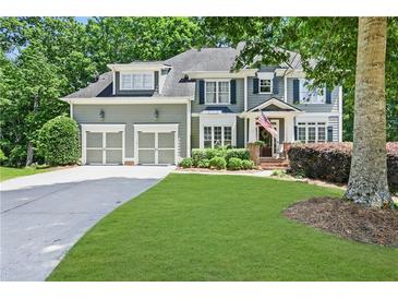 Charming two-story home featuring a manicured lawn, attached garage, and traditional architectural details at 1604 Summersweet Ln, Dacula, GA 30019