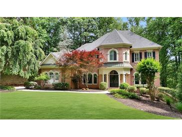 Charming two-story brick home with a manicured lawn, mature trees and professionally landscaped front yard at 5040 Harrington Rd, Johns Creek, GA 30022