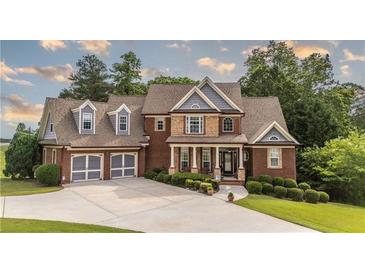 Charming two-story brick home featuring a well-manicured lawn, a driveway to a two-car garage, and decorative landscaping at 9742 Fallview Ct, Villa Rica, GA 30180
