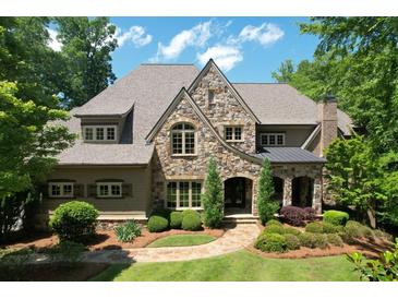 Stunning stone home featuring manicured landscaping, arched entryway, and a charming walkway to the front door at 1023 Little Darby Ln, Suwanee, GA 30024
