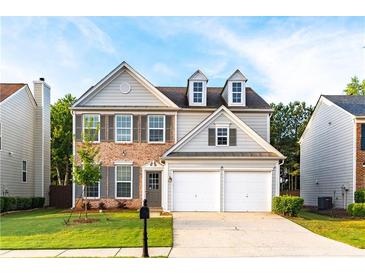 Charming two-story home with brick accents, dormer windows, a two-car garage, and a well-manicured front yard at 8750 Radford Ln, Suwanee, GA 30024