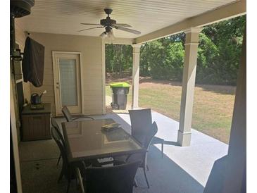 Inviting covered patio with ceiling fan, outdoor seating, and view of the lush backyard at 124 Archstone Sq, Mcdonough, GA 30253