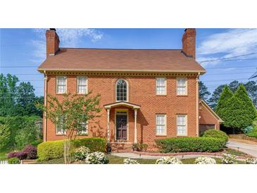 Charming brick two-story home featuring a landscaped front yard and a classic, symmetrical design at 110 Amsterdam Dr, Lilburn, GA 30047