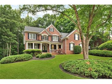 Traditional two-story brick home with well-maintained landscaping and mature shade tree in the front yard at 870 River Cliff Ct, Suwanee, GA 30024