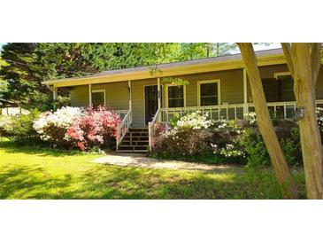 Charming home featuring a quaint front porch and a garden filled with blooming azaleas, showcasing natural beauty at 61 Maxie Ln, Dallas, GA 30157