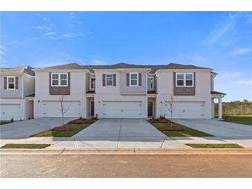 New townhomes featuring symmetrical design, grey shutters, concrete driveway, and manicured landscaping at 321 Heavenly Hollow Pl, Mcdonough, GA 30253