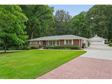 Beautiful red brick home with a lush lawn, mature trees, and a detached two car garage at 2624 Lake Erin Drive Dr, Tucker, GA 30084
