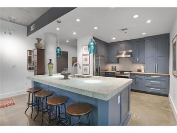 Contemporary kitchen boasts a spacious island, stylish stools, modern lighting, and blue cabinets at 845 Spring Nw St # 129, Atlanta, GA 30308