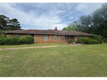 Charming one-story brick home featuring a lush green lawn and established landscaping at 1856 Butler Bridge Rd, Covington, GA 30016
