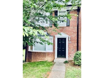 Charming brick home with black door, bay window, and manicured lawn at 401 Autumn Leaf Way, Norcross, GA 30093