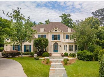 Elegant two-story home with a well-manicured lawn, lush greenery, and a charming stone walkway leading to the front entrance at 8470 Lazy Oaks Ct, Atlanta, GA 30350
