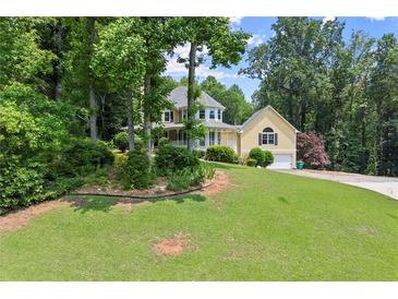Charming yellow two-story home with a wraparound porch and lush green lawn at 1713 Dudley Dr, Woodstock, GA 30188