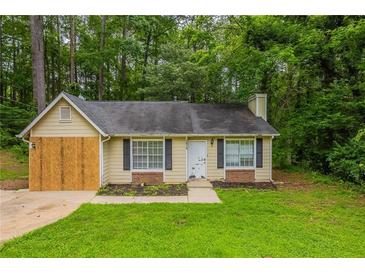 Charming one-story house with black shutters and a well-maintained lawn surrounded by lush greenery at 5856 Rock Rd, Union City, GA 30291