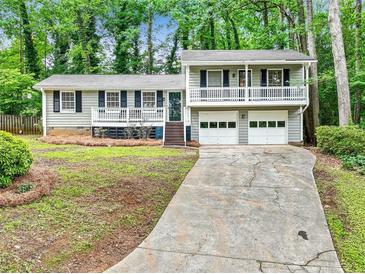 Charming home featuring a two-car garage, wood siding, and a cozy front porch, nestled among mature trees at 604 Continental Dr, Lawrenceville, GA 30044