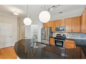Updated kitchen features stainless steel appliances, granite countertops, and pendant lighting at 3621 Vinings Slope Se # 3510, Atlanta, GA 30339