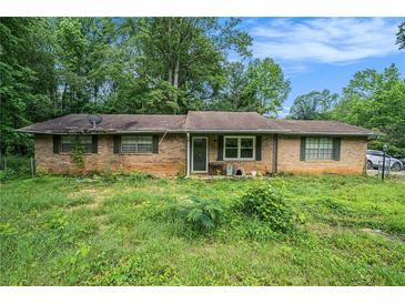 Ranch-style home featuring a brick exterior, surrounded by trees, and a spacious front yard at 2087 Chestnut Way, Lithia Springs, GA 30122