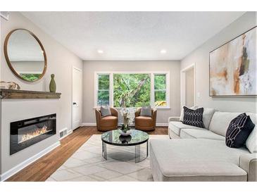 Inviting living room featuring a fireplace, hardwood floors, and large windows offering plenty of natural light at 522 Stell Rd, Woodstock, GA 30188
