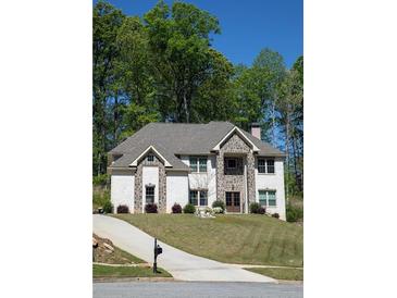 Charming two-story home with white brick, stone accents, manicured lawn, and lush trees at 5663 Eternal Dr, Atlanta, GA 30349
