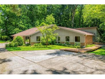 Ranch home featuring horizontal siding, brick accents, a large yard and mature trees at 1690 Trotters Ln, Stone Mountain, GA 30087
