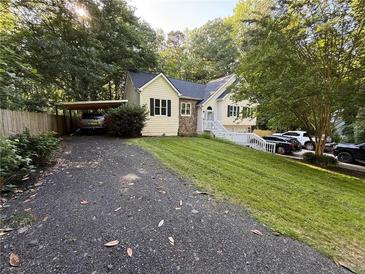 Charming two-story home with landscaped yard, a carport, and ample parking space on a sunny day at 5640 Rolling Oaks Dr, Cumming, GA 30040