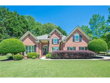 Charming brick home featuring a well-manicured front lawn, mature trees, and classic architectural details at 7045 Grand View Way, Suwanee, GA 30024