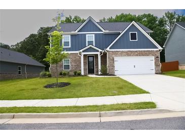 Charming two-story home featuring blue siding, brick accents, a well-manicured lawn, and an attached two-car garage at 3855 Saddle Bag Ct, Dacula, GA 30019