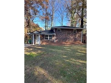 Charming brick home featuring a well-maintained lawn and mature trees providing shade at 4510 Burks Rd, Forest Park, GA 30297