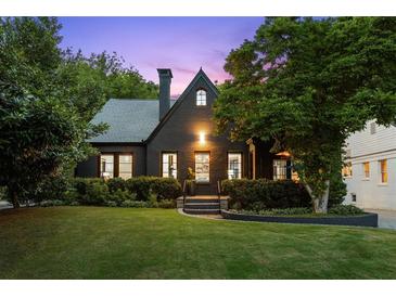 Charming two-story home with dark exterior, manicured lawn, and mature trees at 570 Martina Ne Dr, Atlanta, GA 30305