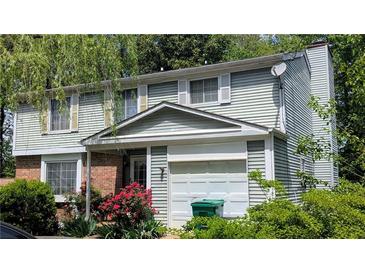 Two-story home with light-green vinyl siding, brick accents, white trim, and a one-car garage at 4256 Village Square Ln, Stone Mountain, GA 30083