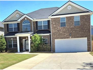 Charming two-story brick home with a well-manicured lawn, two-car garage, and inviting entrance at 5030 Mundy Dr, Cumming, GA 30028
