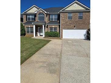 Two story brick home featuring a well manicured front yard and attached two car garage at 5030 Mundy Dr, Cumming, GA 30028