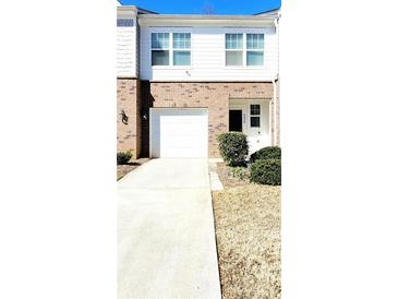 Two-story townhome with white siding, brick accents, an attached garage, and well-maintained landscaping at 6408 Kennonbriar Ct, Lithonia, GA 30058