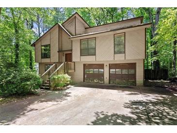 Two-story home with wood siding, two-car garage, stairs leading to front door, and mature trees at 4949 Woodland Nw Way, Acworth, GA 30102
